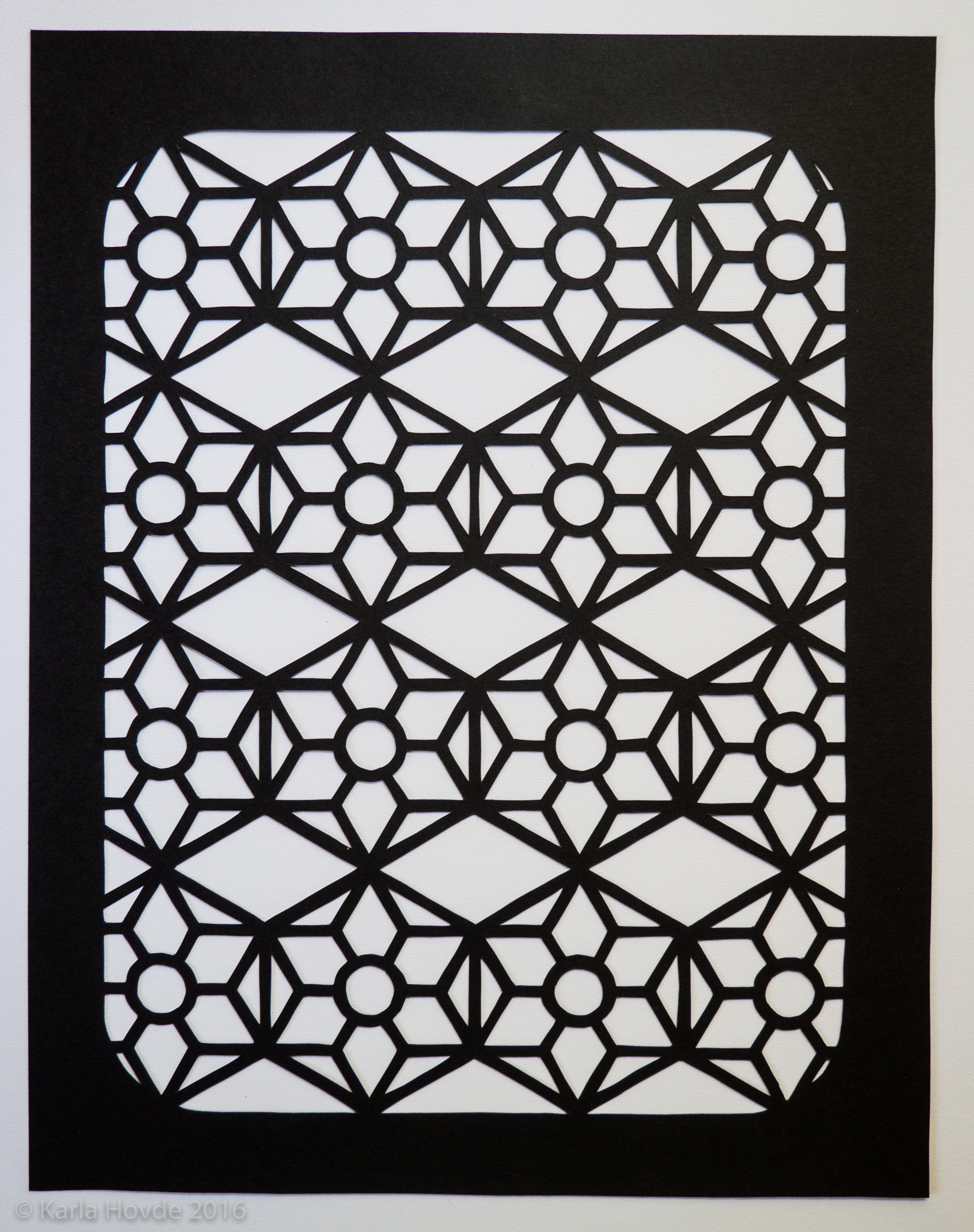 Paper cutting art in black paper shows delicate geometric arabesque pattern.